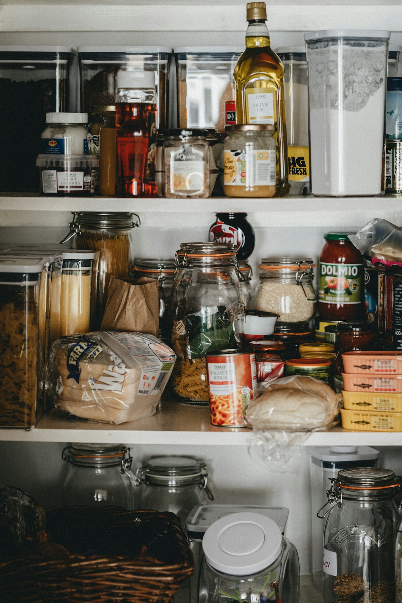 Clear glass storage jars on a white pantry shelf