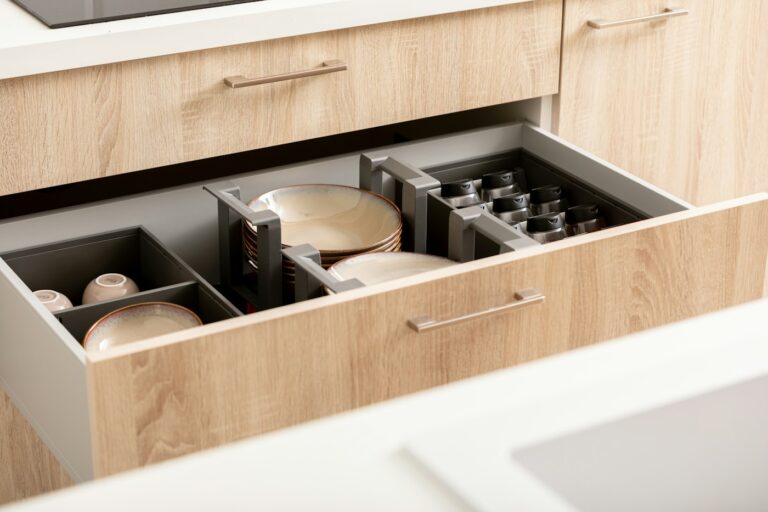An open kitchen drawer filled with neatly stacked dishes