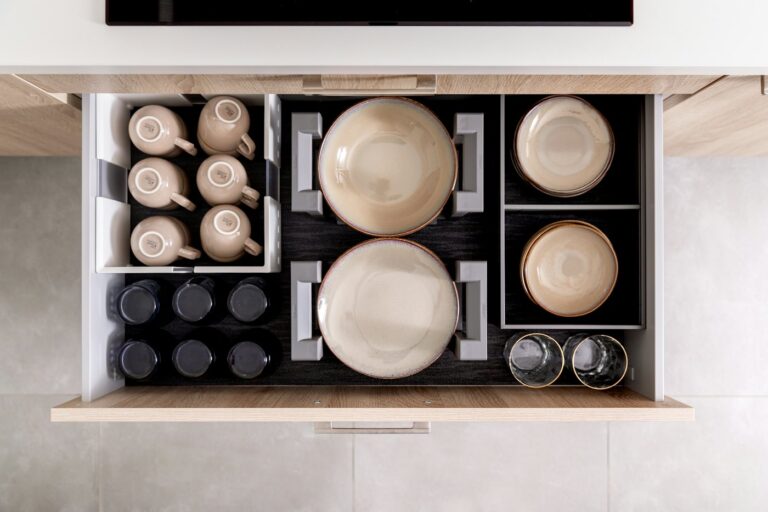 A deep kitchen drawer holding dishes and cups